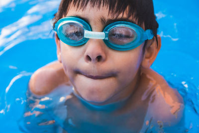 Portrait of cute boy wearing swimming goggles in pool