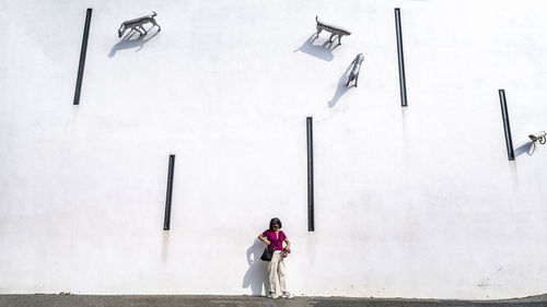 Rear view of woman walking on white wall