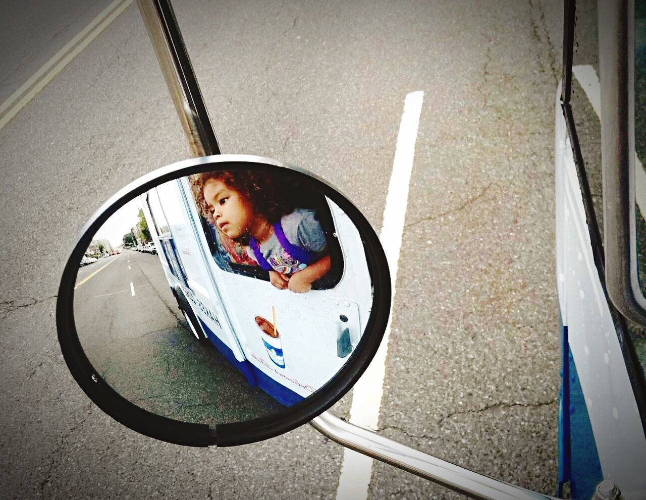 Reflection of girl on side-view mirror of truck window