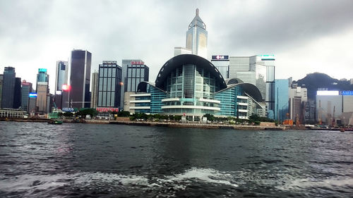 City at waterfront against cloudy sky