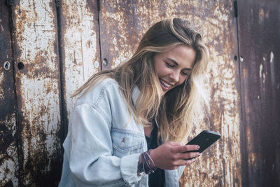Young woman using mobile phone while standing at home
