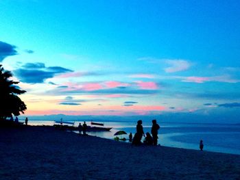 Silhouette people on beach against sky during sunset