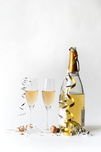 Two champagne glasses and bottle and against white background.