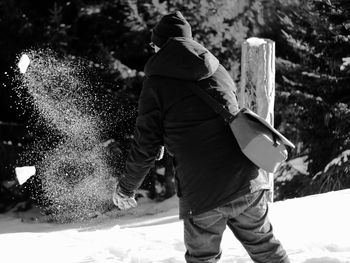 Rear view of man playing with snow