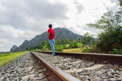 Full length of man standing on railroad track against sky