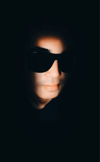 Close-up of man wearing sunglasses against black background