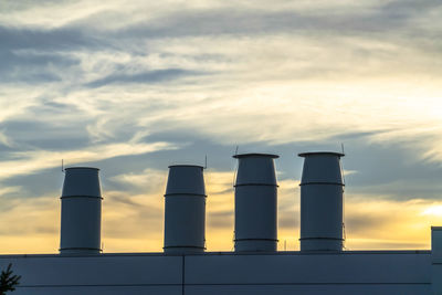 Low angle view of smoke stack against sky during sunset