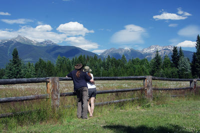 Full length of man and woman standing on field against sky