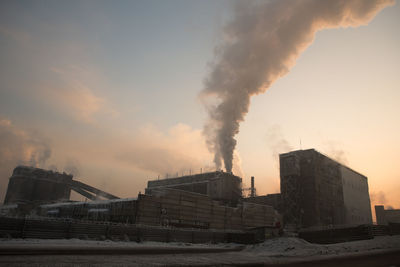 Smoke emitting from factory against sky during sunset