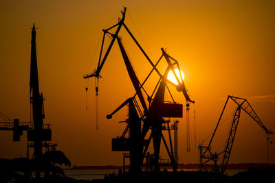 Silhouette cranes against sky at sunset at port of pula, croatia