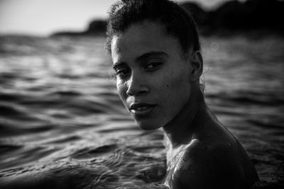Close-up portrait of shirtless young woman swimming in sea