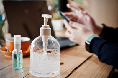 Close-up of hand holding glass bottle on table