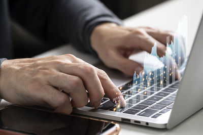 Midsection of businessman using laptop on table