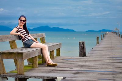 Woman sitting on wooden table against sky