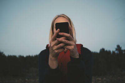 Woman using mobile phone while sitting in boat against blue sky