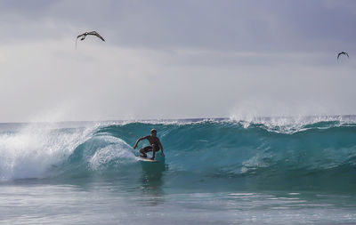 Man surfing in sea against sky