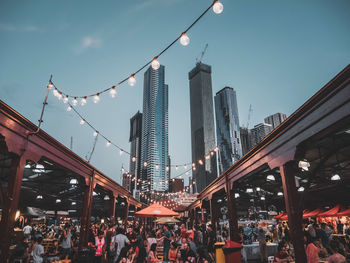 People on street amidst buildings in city against sky