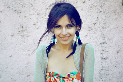 Portrait of happy beautiful woman standing by wall