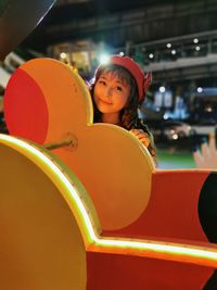 Portrait of girl playing with carousel in amusement park