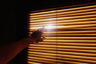 Cropped hand of person touching window blinds