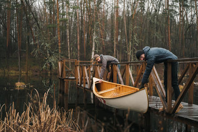 Men holding rowboat from lake