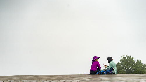 Women talk sitting on top against sky