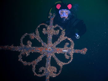 Portrait of mid adult woman holding metal while swimming undersea