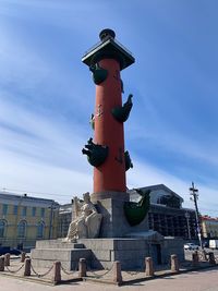 Low angle view of statue by building against sky