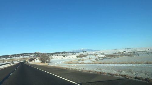 Road against clear blue sky during winter