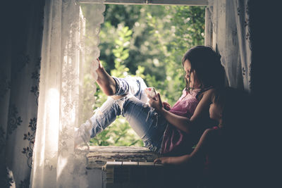 Kid girl on the box with the phone, the concept of sadness and loneliness, problems with gadgets