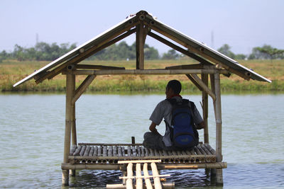 Rear view of man on river against sky