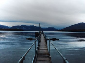 Pier on lake against cloudy sky