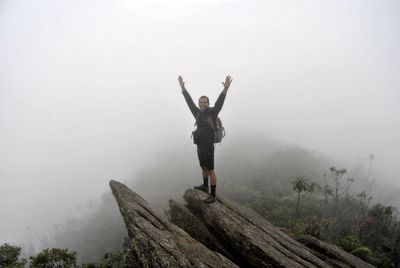 Man with arms outstretched standing on mountain