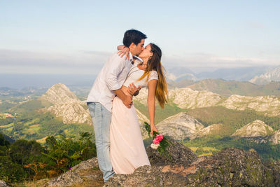 Young couple standing on mountain against sky
