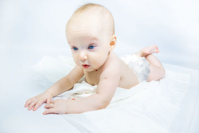 Portrait of cute baby girl lying on bed at home