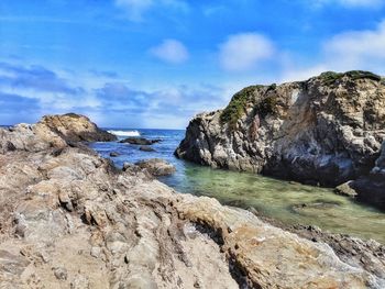 Rock formation on beach against sky