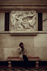 Woman standing statue against wall