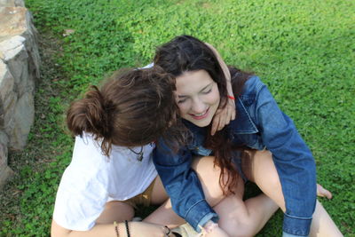 High angle view of woman kissing girlfriend while sitting on land in park