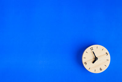 Close-up of wooden clock on blue background