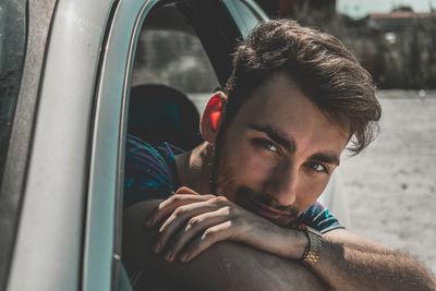 Close-up portrait of young man looking through car window