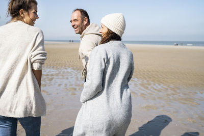 Rear view of friends on beach against sky