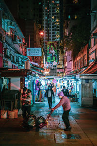 People on street against illuminated buildings in city at night