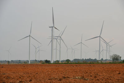 Windmills on field against clear sky