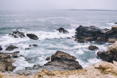 Scenic view of rocks in sea against sky