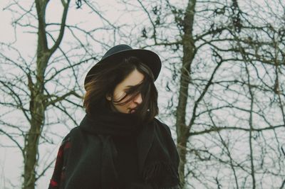 Portrait of woman standing by bare tree during winter