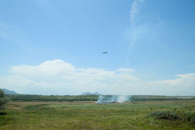 Airplane flying over field against sky