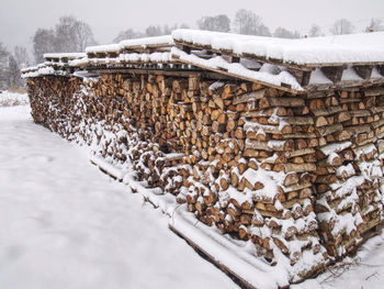 Chopped stock of firewood under snow, regular pile from cut wood