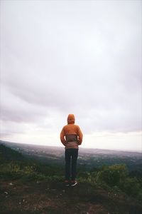 Rear view of man standing on landscape against sky