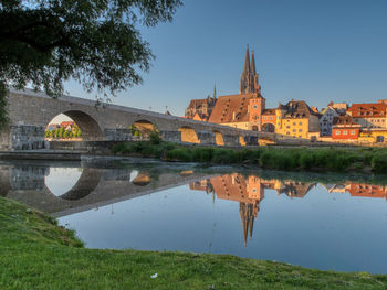 Arch bridge over river amidst buildings against sky