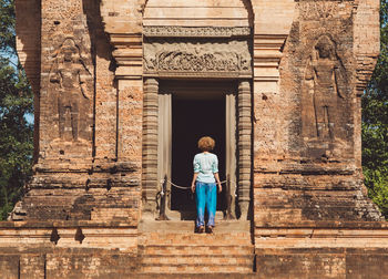 Full length rear view of woman walking in historic building